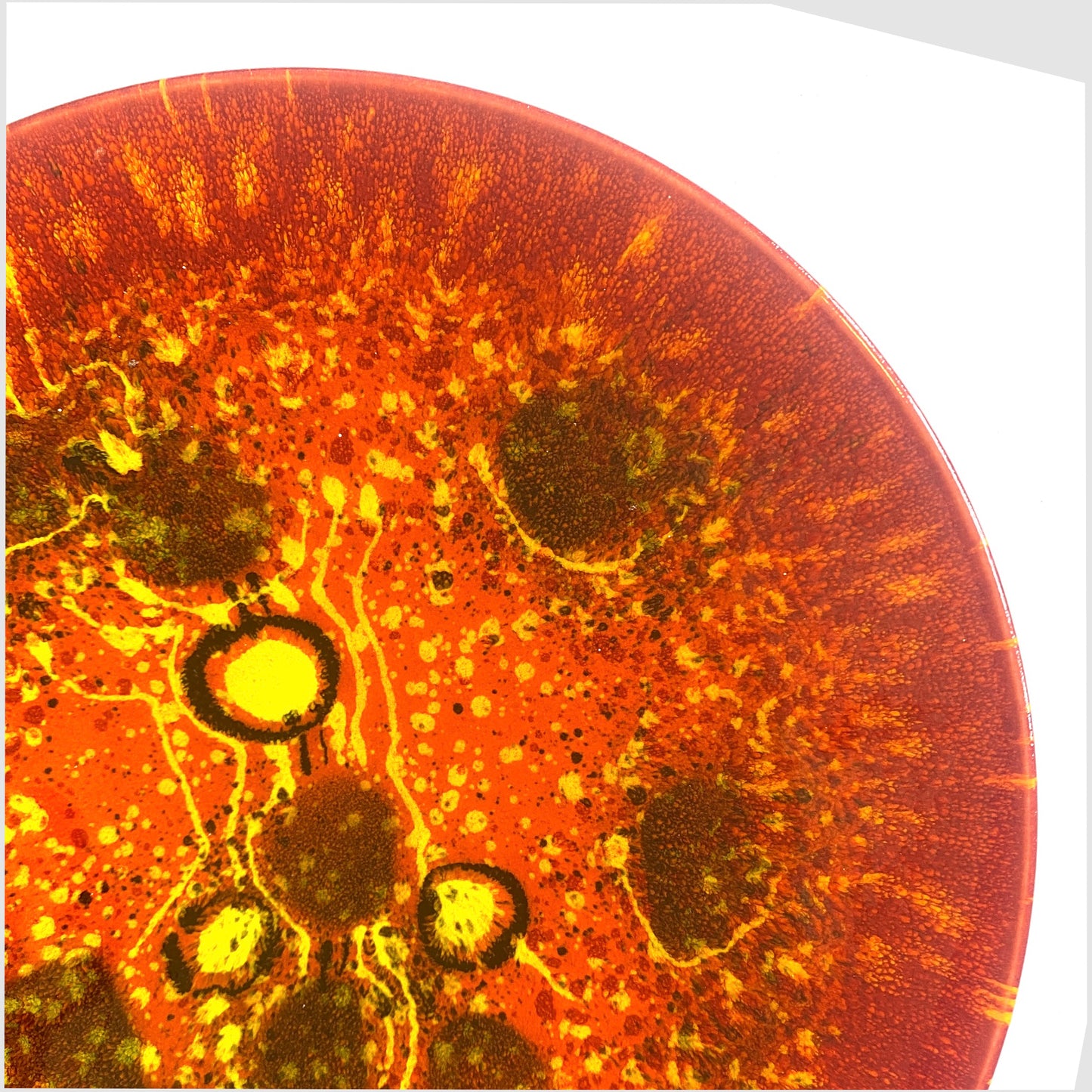 close up of the poole pottery alignment of the planets venus plate glazed in fiery red and orange with yellow spheres