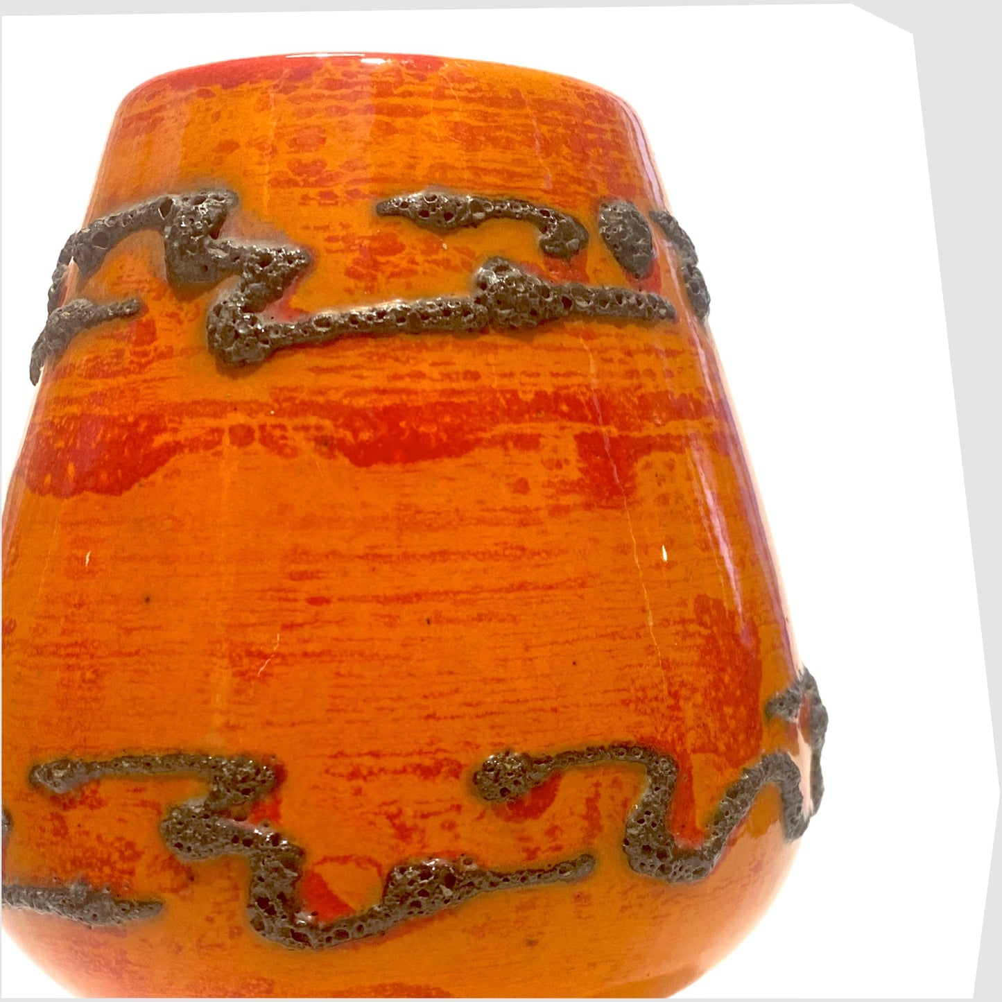 Decorative orange West German pottery vase with black fat lava patterns on a white background