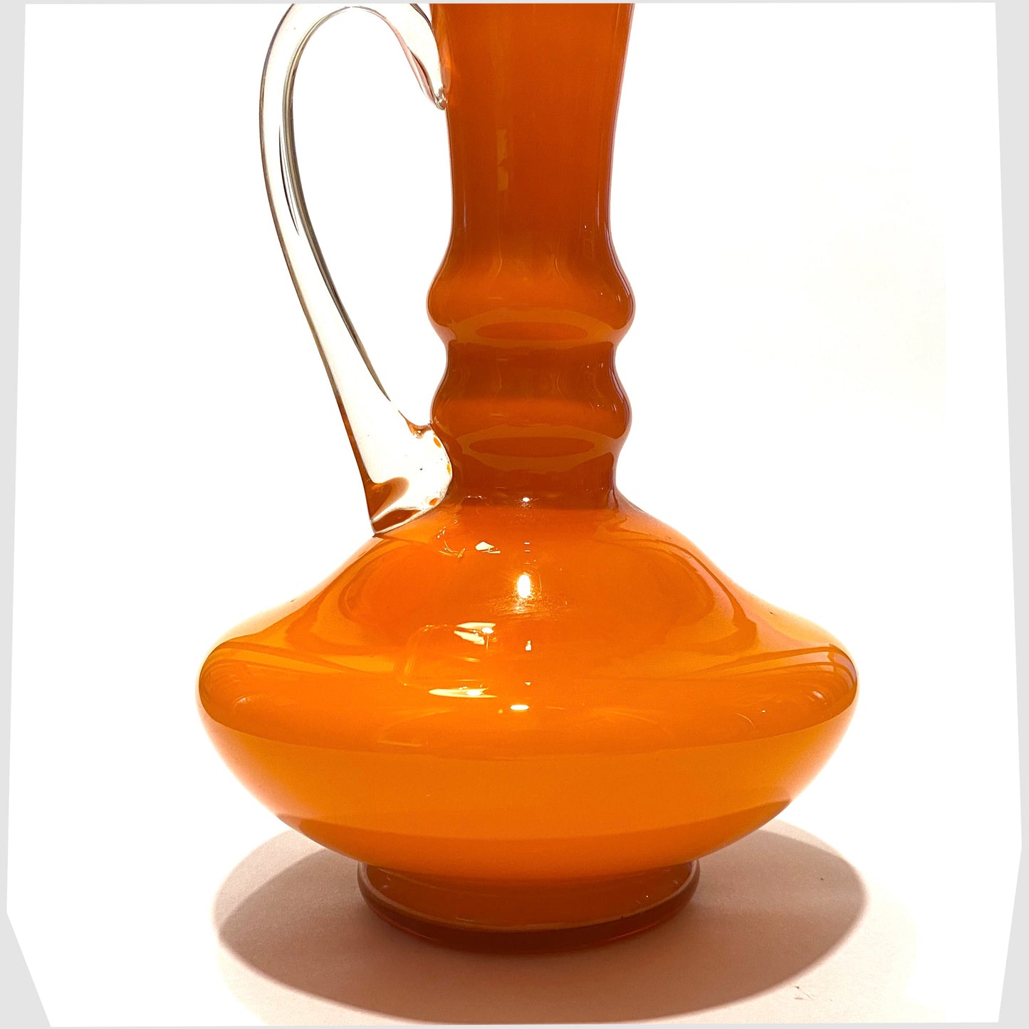 hooped body of the italian empoli glass jug in vibrant orange cased glass with clear glass handle