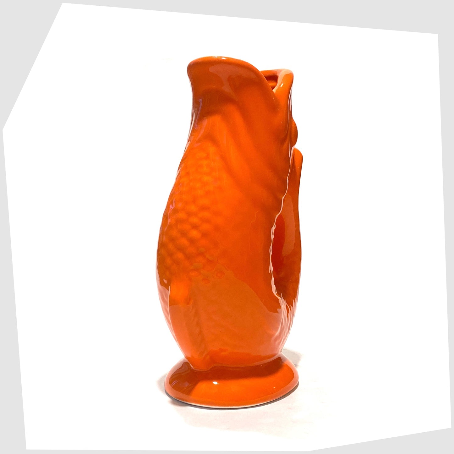 front of the fish-shaped ceramic vase in bold orange glaze