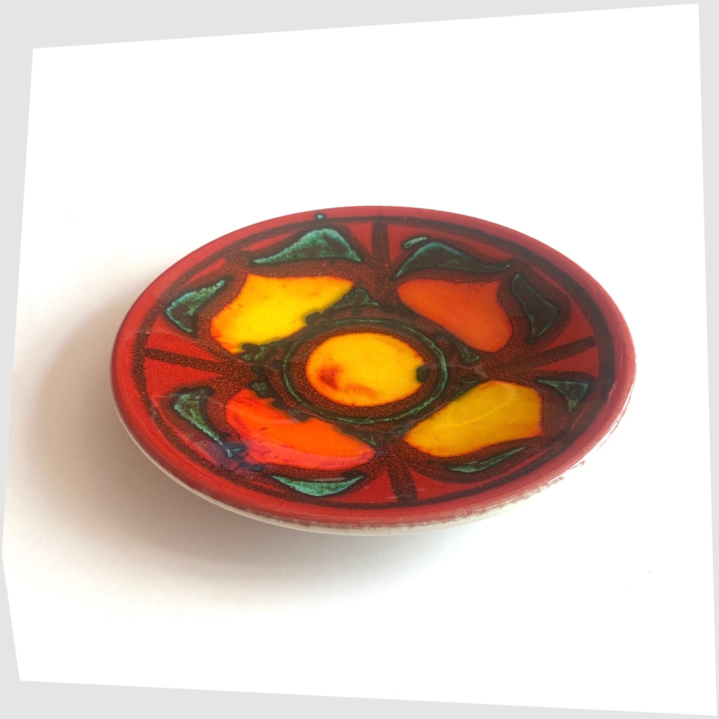 1970s Poole Pottery Delphis Pin Dish by Janet Laird in a vibrant red glaze with radiating forms of rich yellow and green, shown on a white background