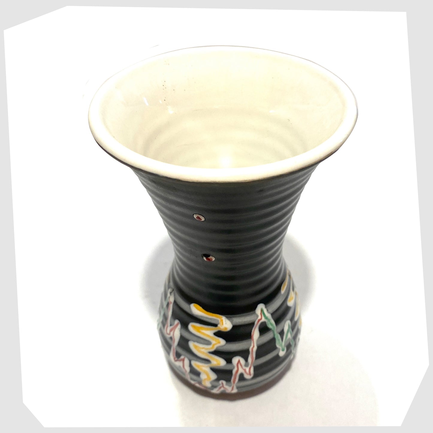 top rim of the 1960s West German Pottery Vase in black glaze with with artistic lines of yellow, green and red glaze, shown on a white background