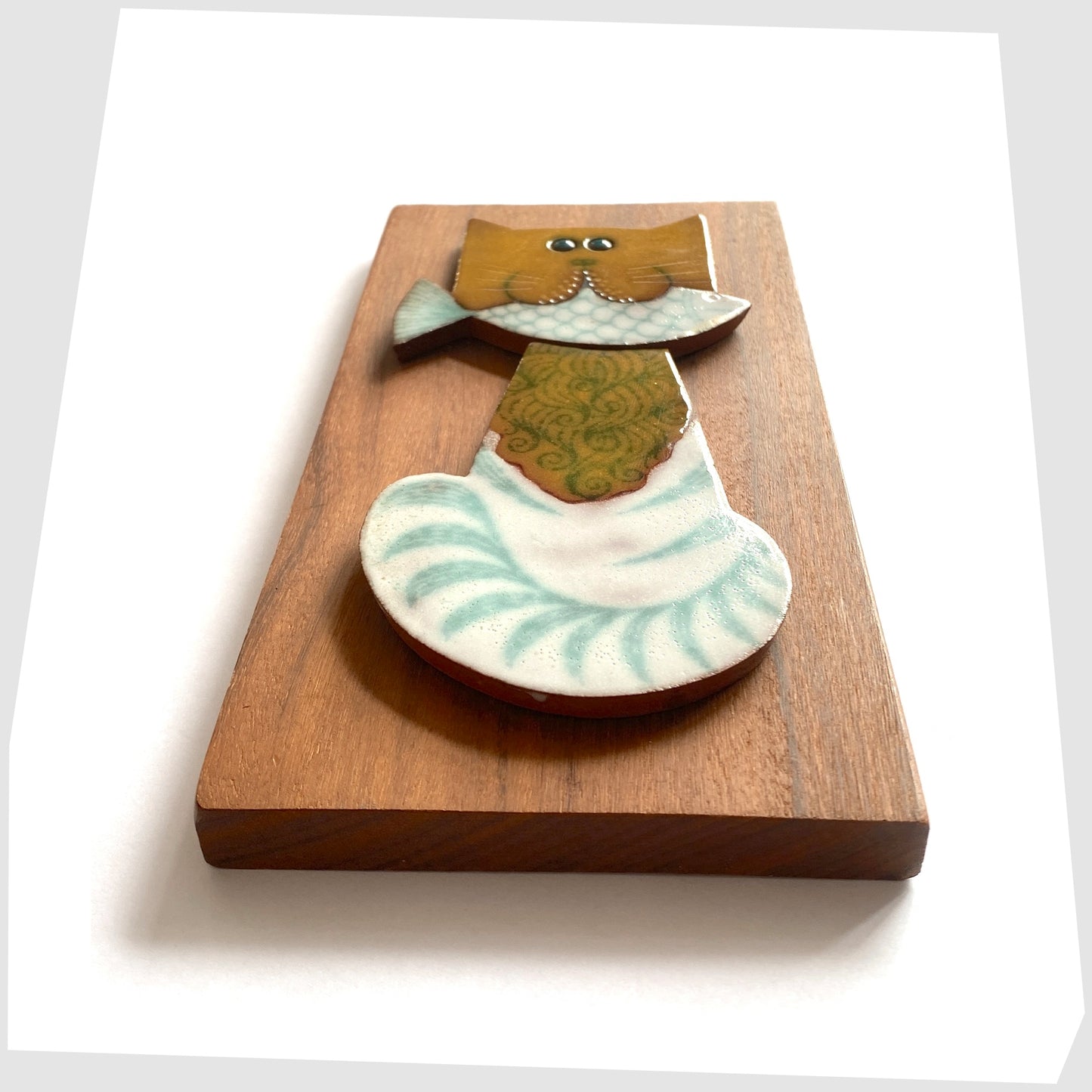 vintage hornsea muramic wall plaque showning a cat holding a white fish in its mouth, mounted on a wooden plaque