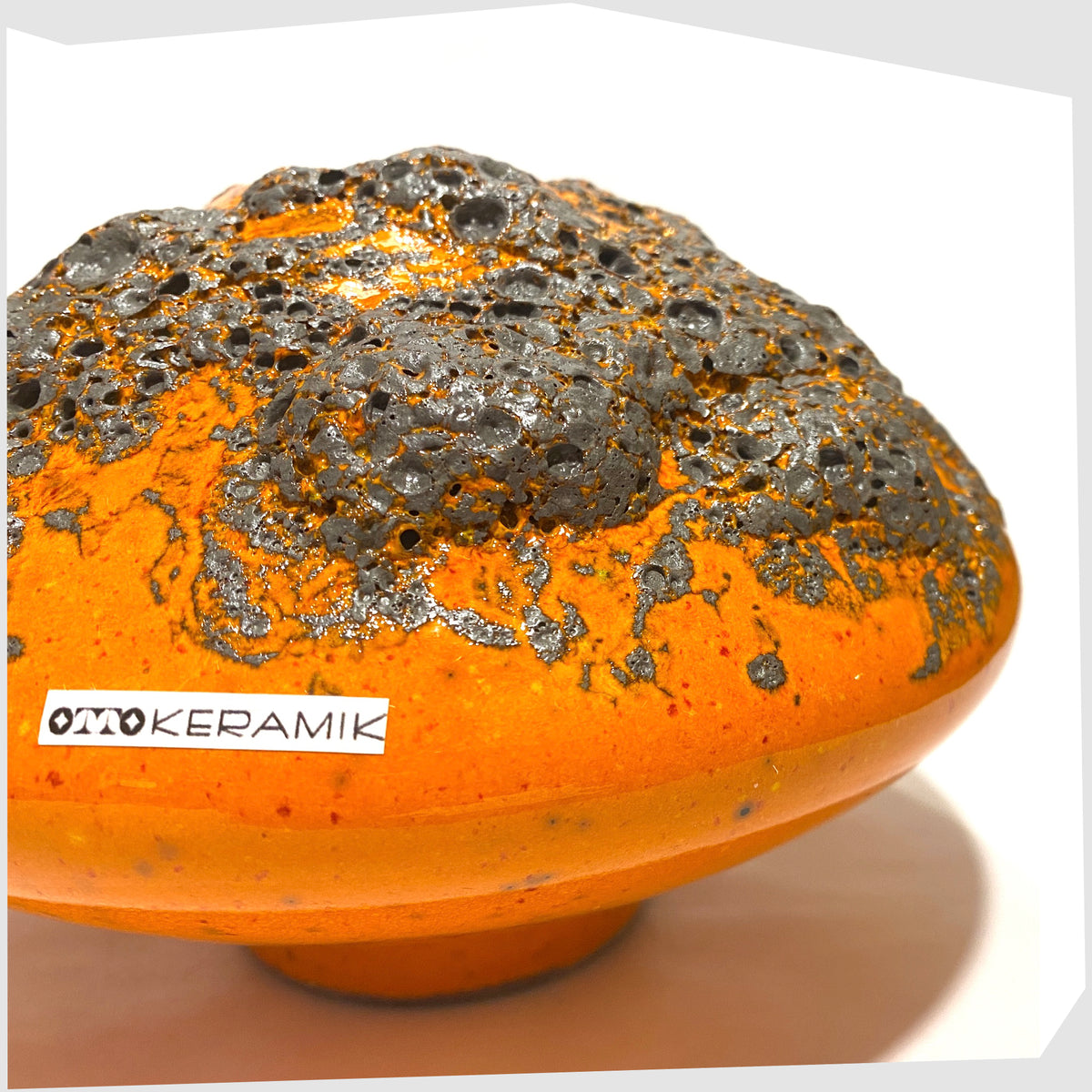 Close up of the Otto Keramik Vase, model 203, in a vibrant orange glaze with grey fat lava, shown on a white background