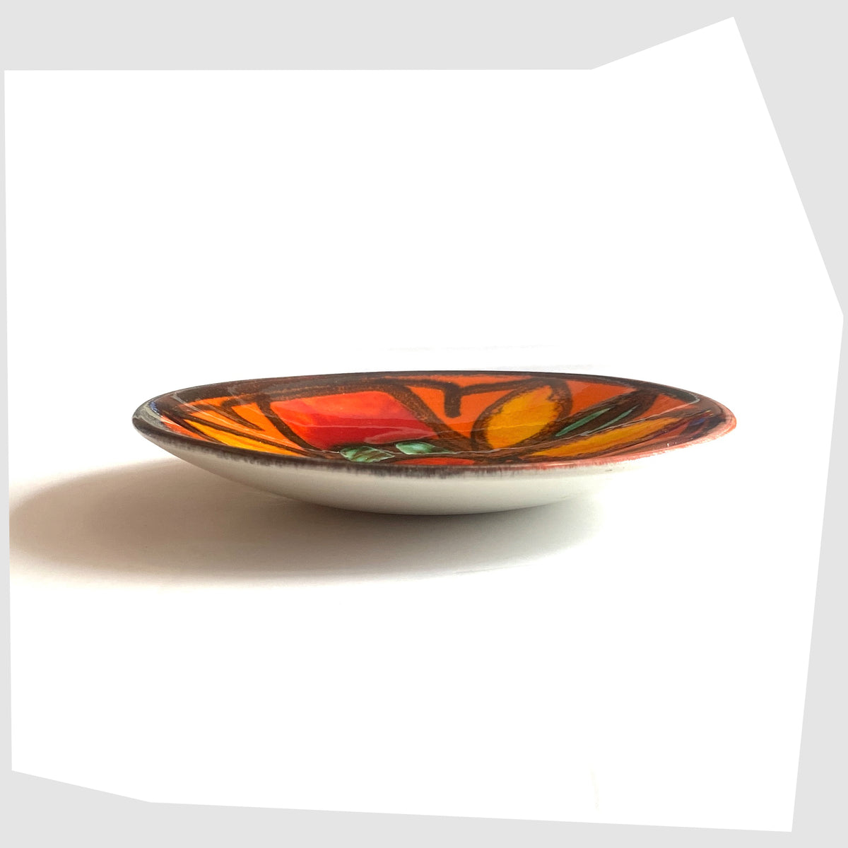 Side profile of the Poole Pottery Delphis Pin Dish, shape 49, by Janet Laird glazed in a vivid orange with fluid forms of green and yellow glaze- Shown on a white background