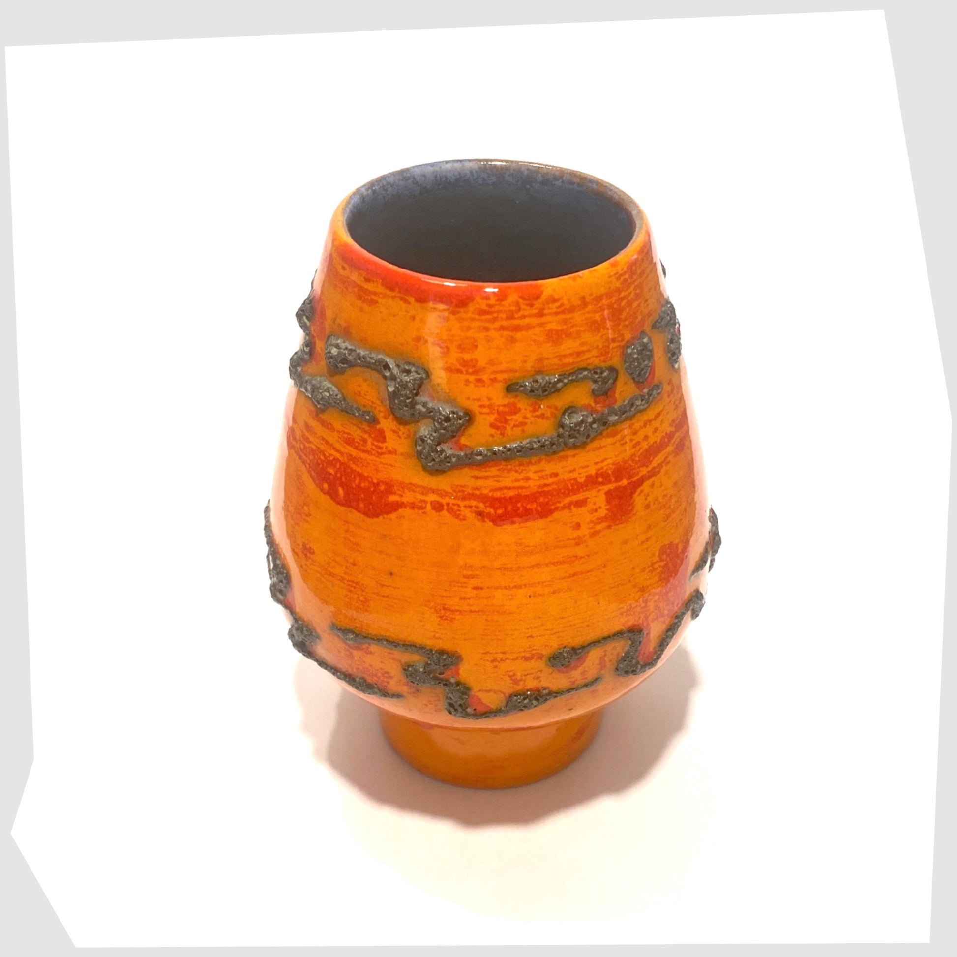 Orange ceramic vase with black decorative patterns of fat lava glaze on a white background
