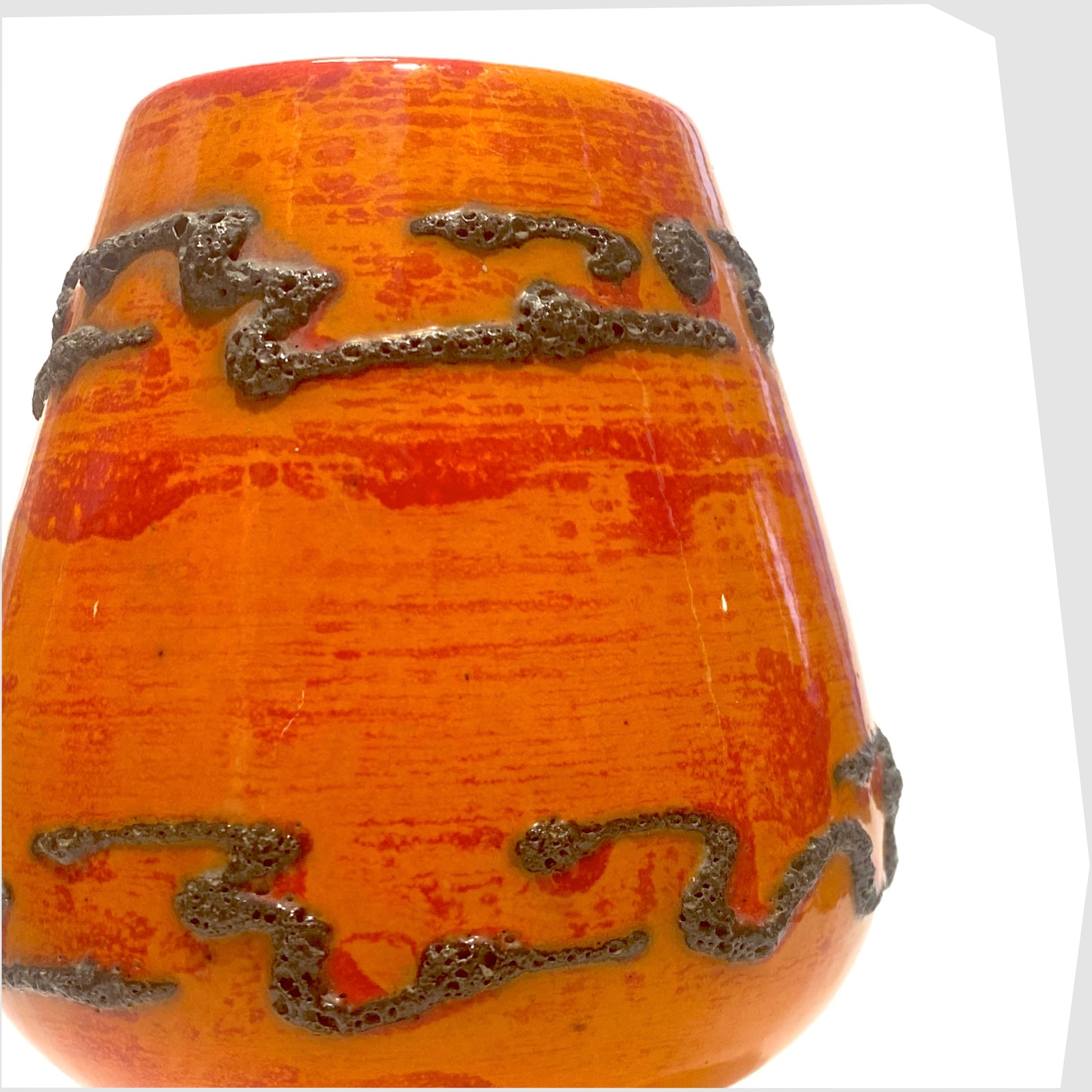 Decorative orange West German pottery vase with black fat lava patterns on a white background