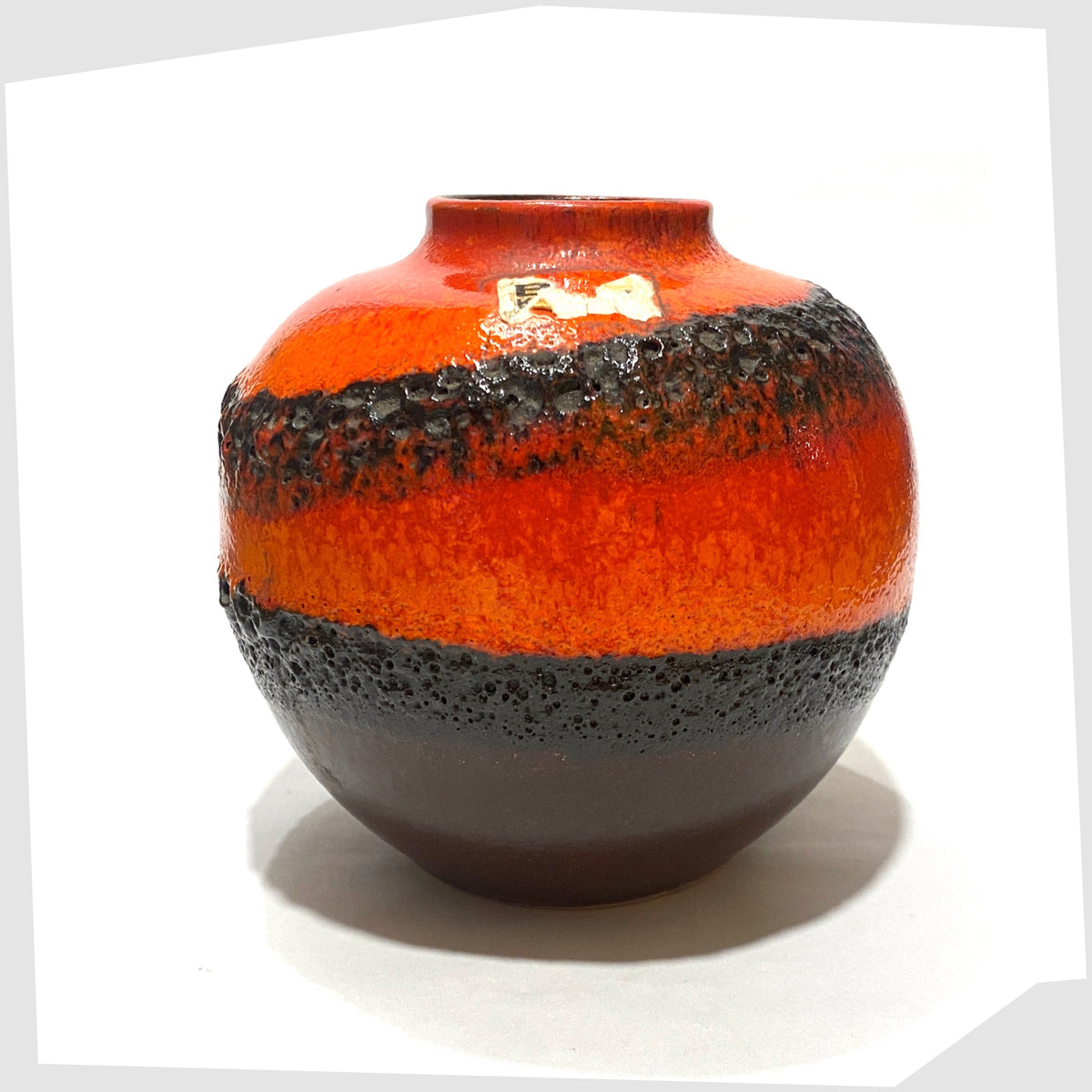 Bay Keramik, model 64-12, with volcanic red and orange glaze with bands of black fat lava, shown on a white background