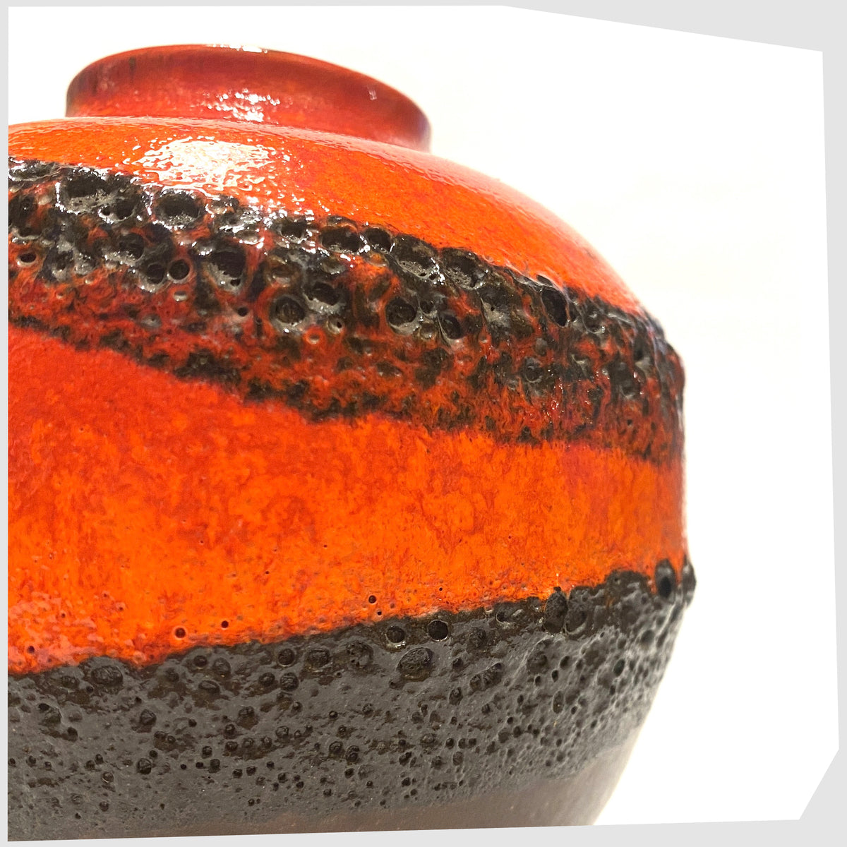 Close up of the West German Pottery Vase by Bay Keramik, model 64-12, with volcanic red and orange glaze with bands of black fat lava, shown on a white background