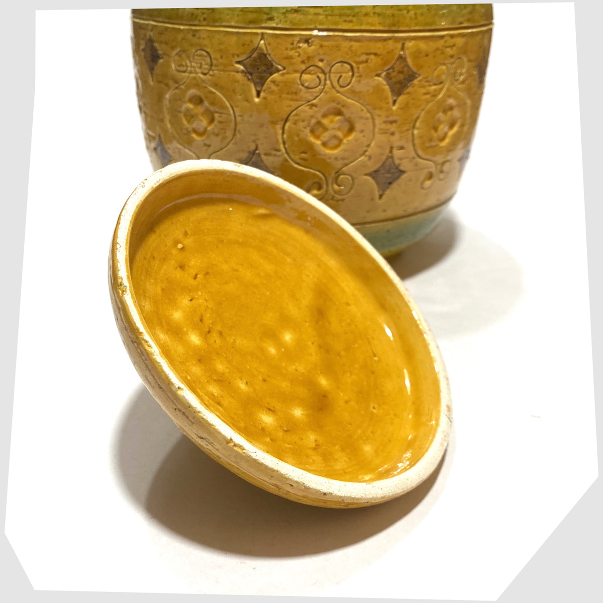 Base of the lid on the Bitossi Arabesque Lidded Jar in yellow glaze with green bands and impressed markings, shown on a white background