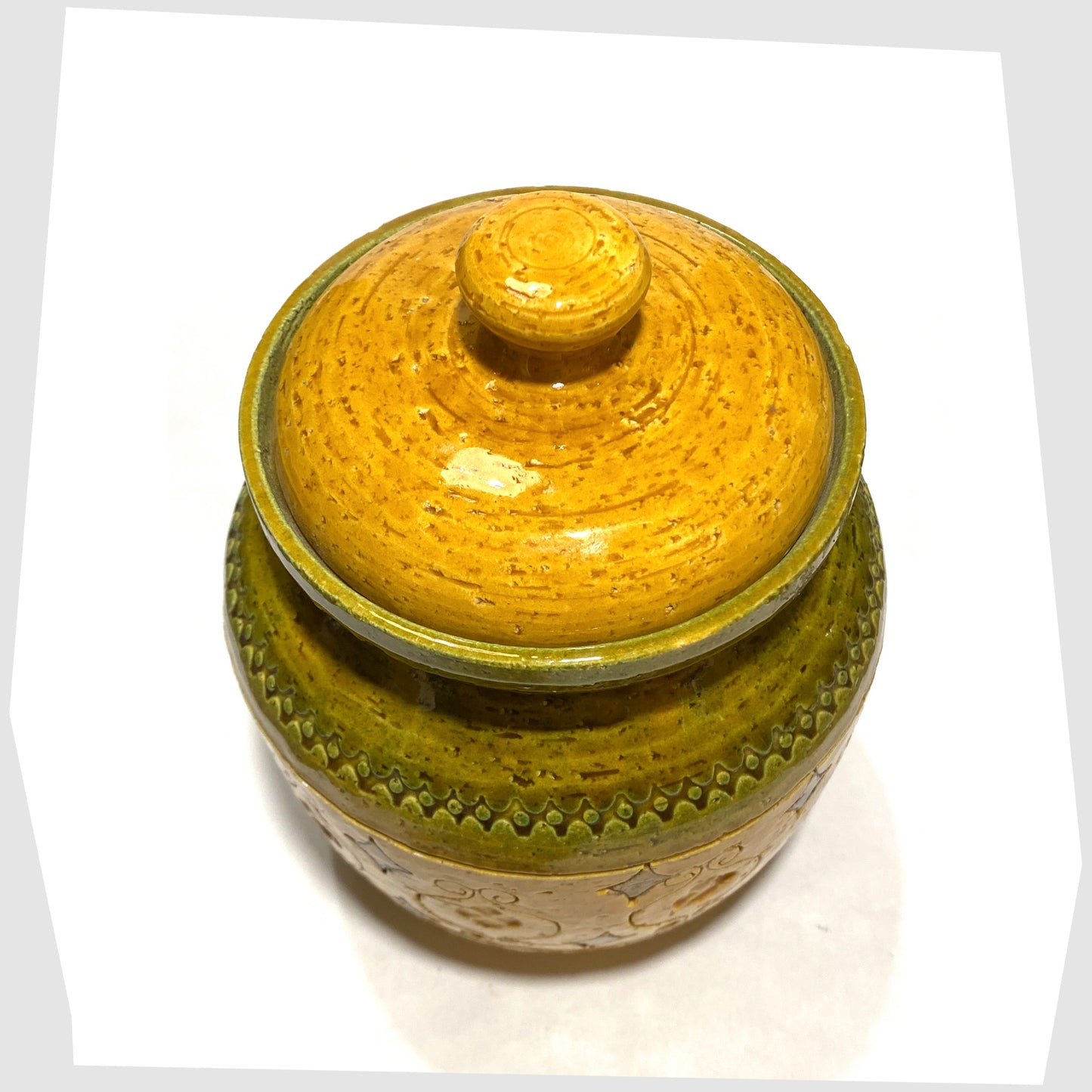 Lid of the Bitossi Arabesque Lidded Jar in yellow glaze with green bands and impressed markings, shown on a white background