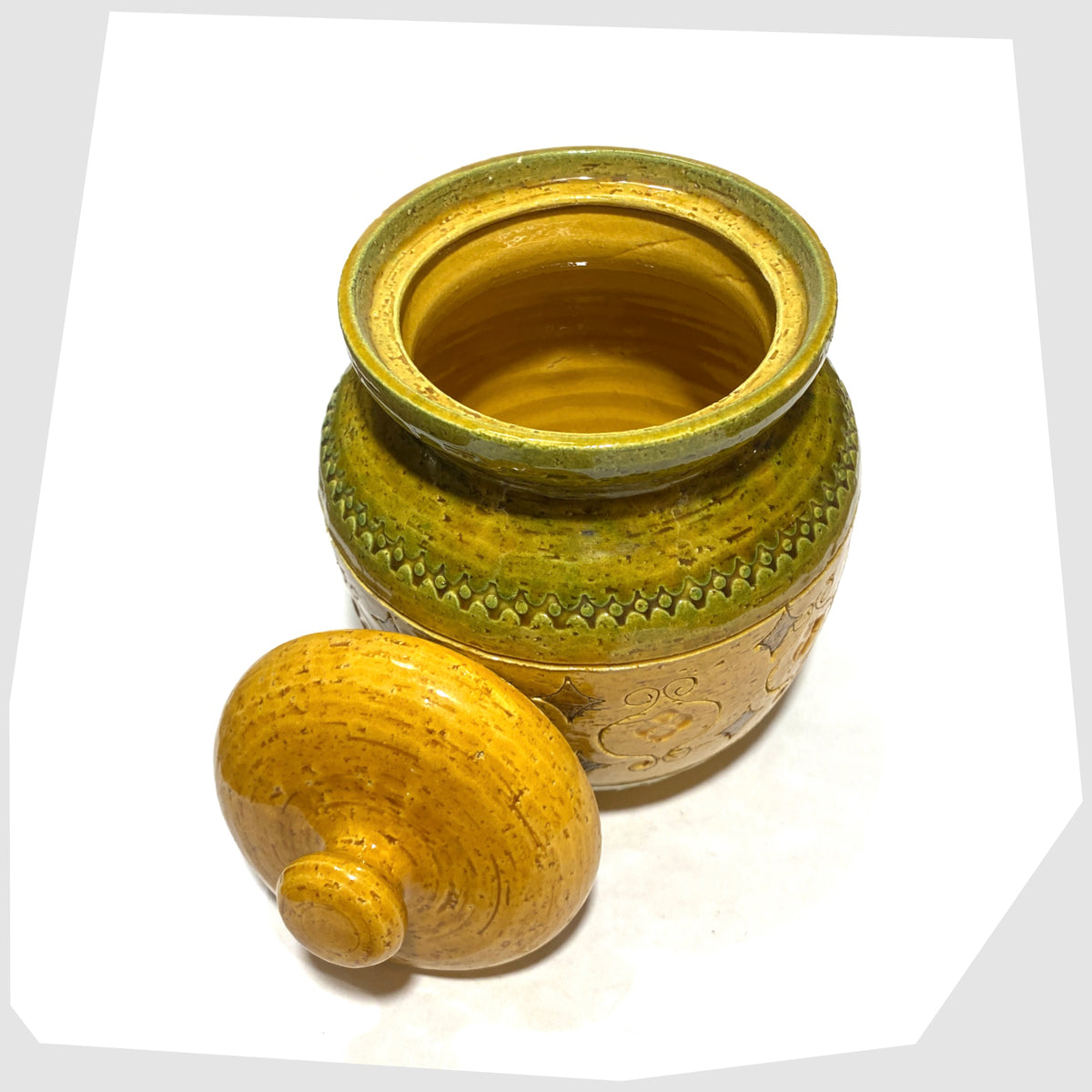 Inside of the Bitossi Arabesque Lidded Jar in yellow glaze with green bands and impressed markings, shown on a white background