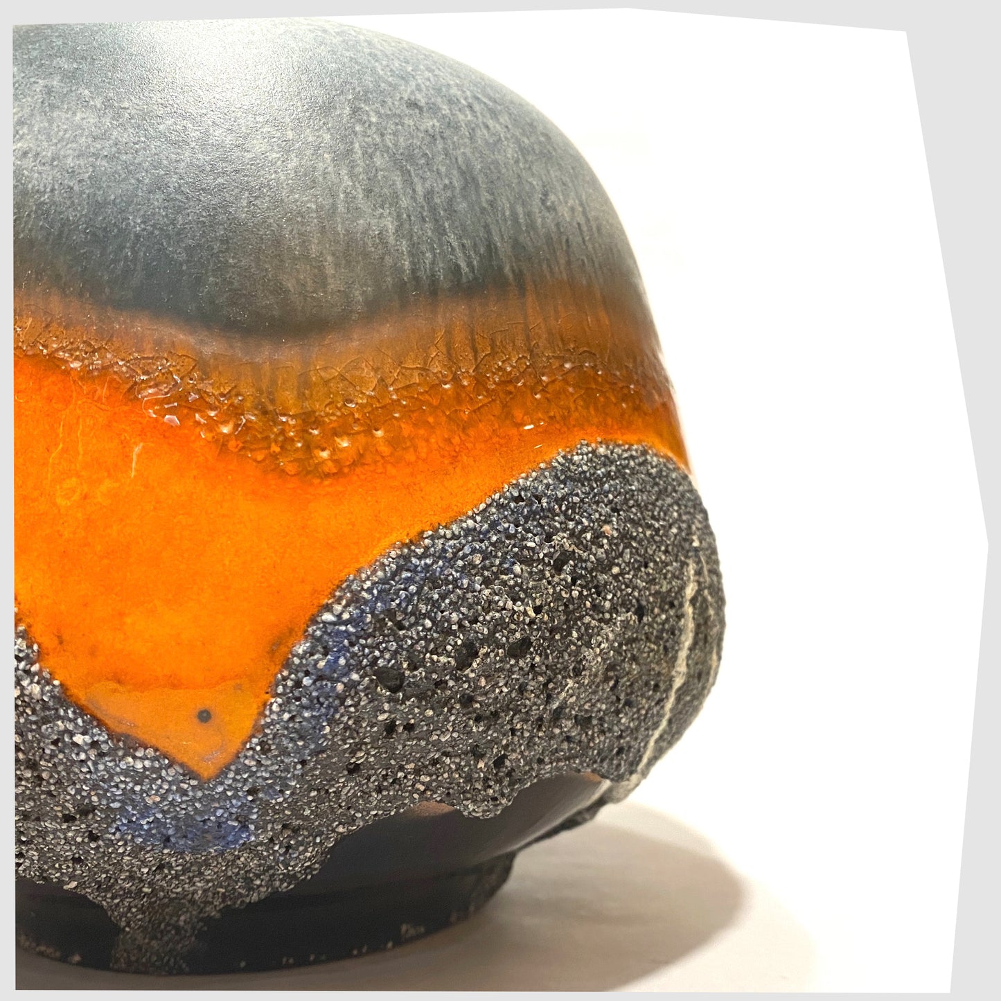 Close up of the Carsten Tonnieshof Vase in asteroid form with bands of cool grey, volcanic orange and blue fat lava