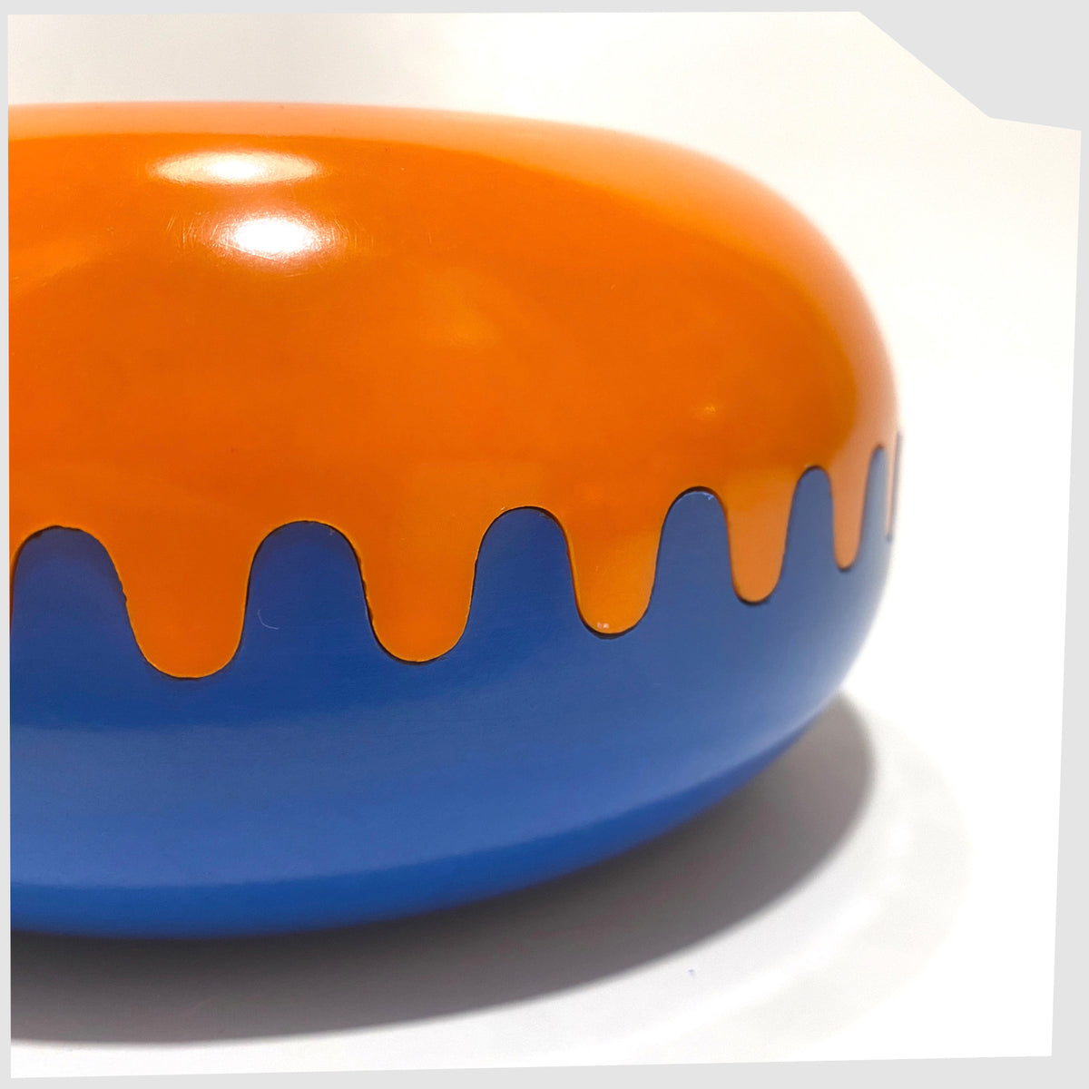 Close up of the Clam Ashtray in Orange and Blue, designed by Alan Fletcher for Pentagram design in 1972, shown on a white background