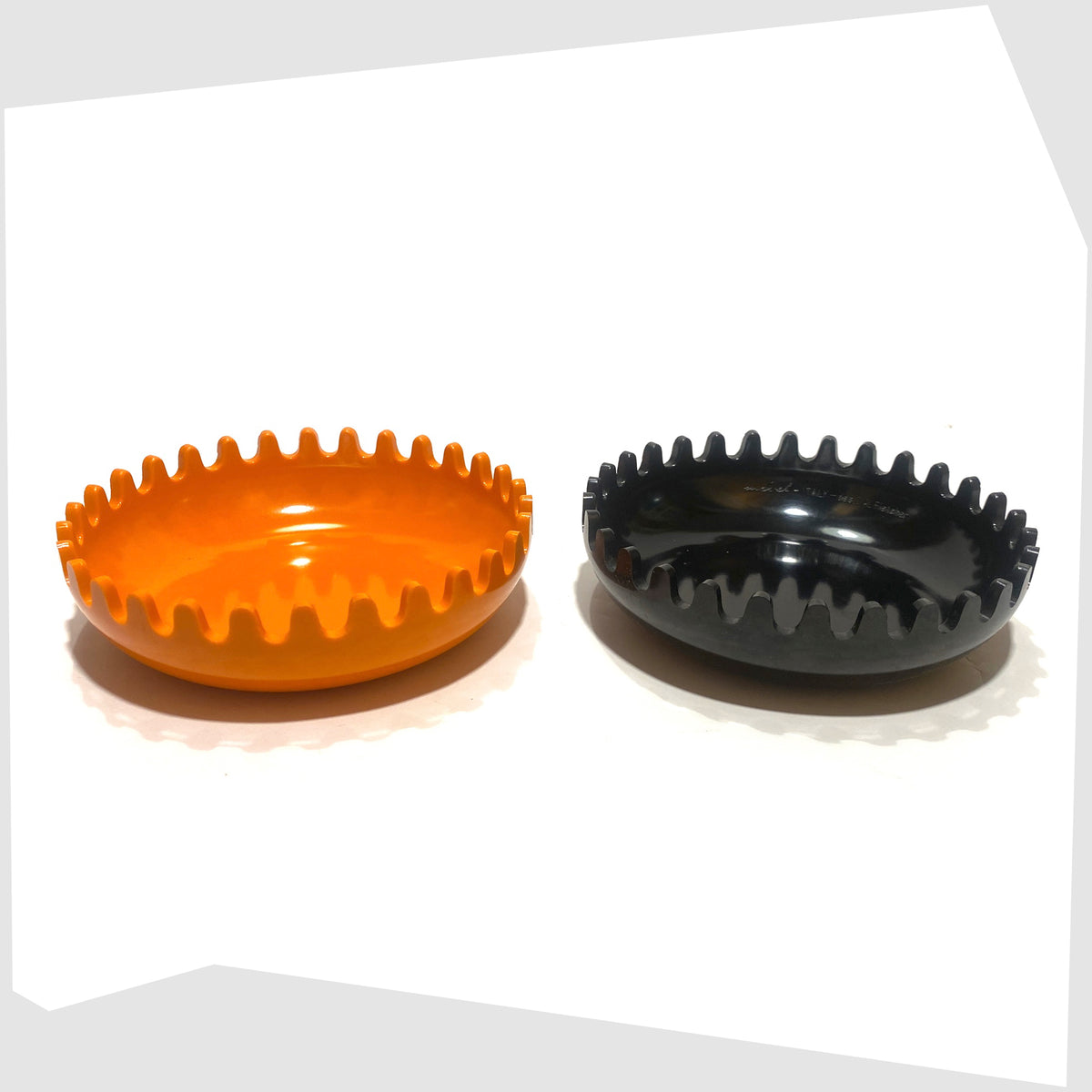 Open Clam Ashtray designed by Alan Fletcher for Pentagram Design in half orange and half black, shown on a white background