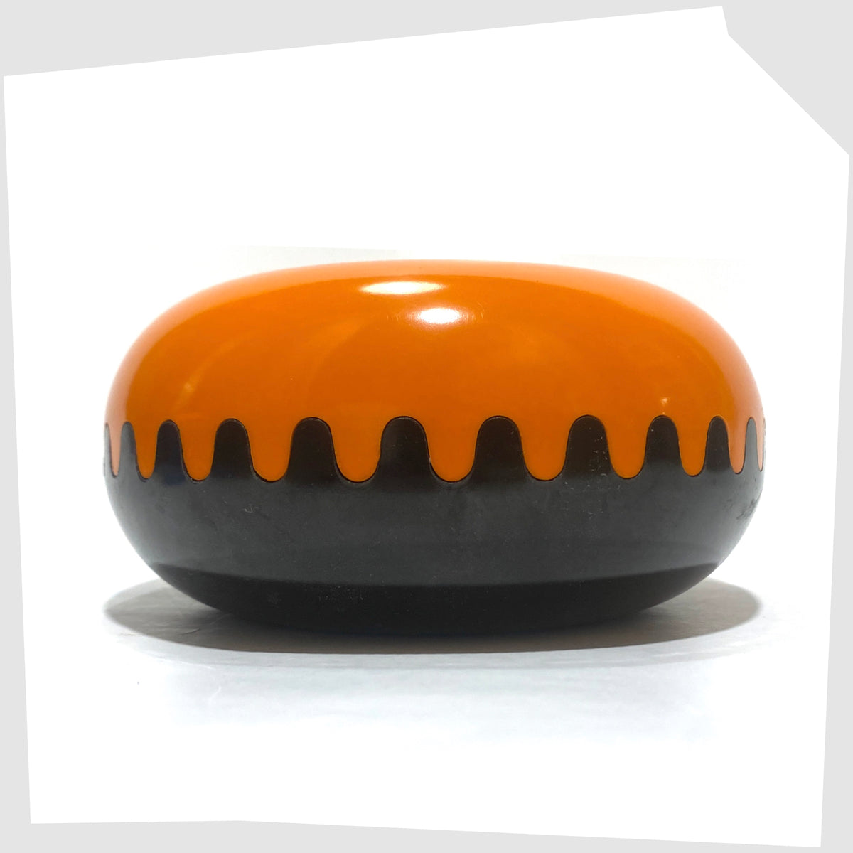 Clam Ashtray designed by Alan Fletcher for Pentagram Design in half orange and half black, shown on a white background