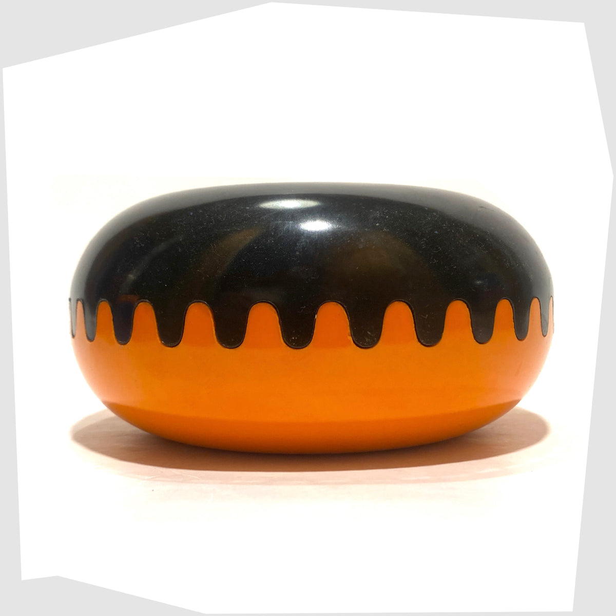 Mebel Clam Ashtray designed by Alan Fletcher for Pentagram Design in half orange and half black, shown on a white background