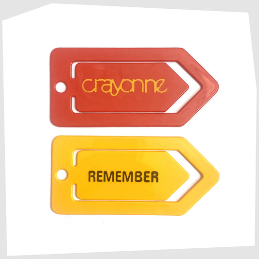 Crayonne Remember Paper Clip in mustard yellow, shown with a red Crayonne advertising tag