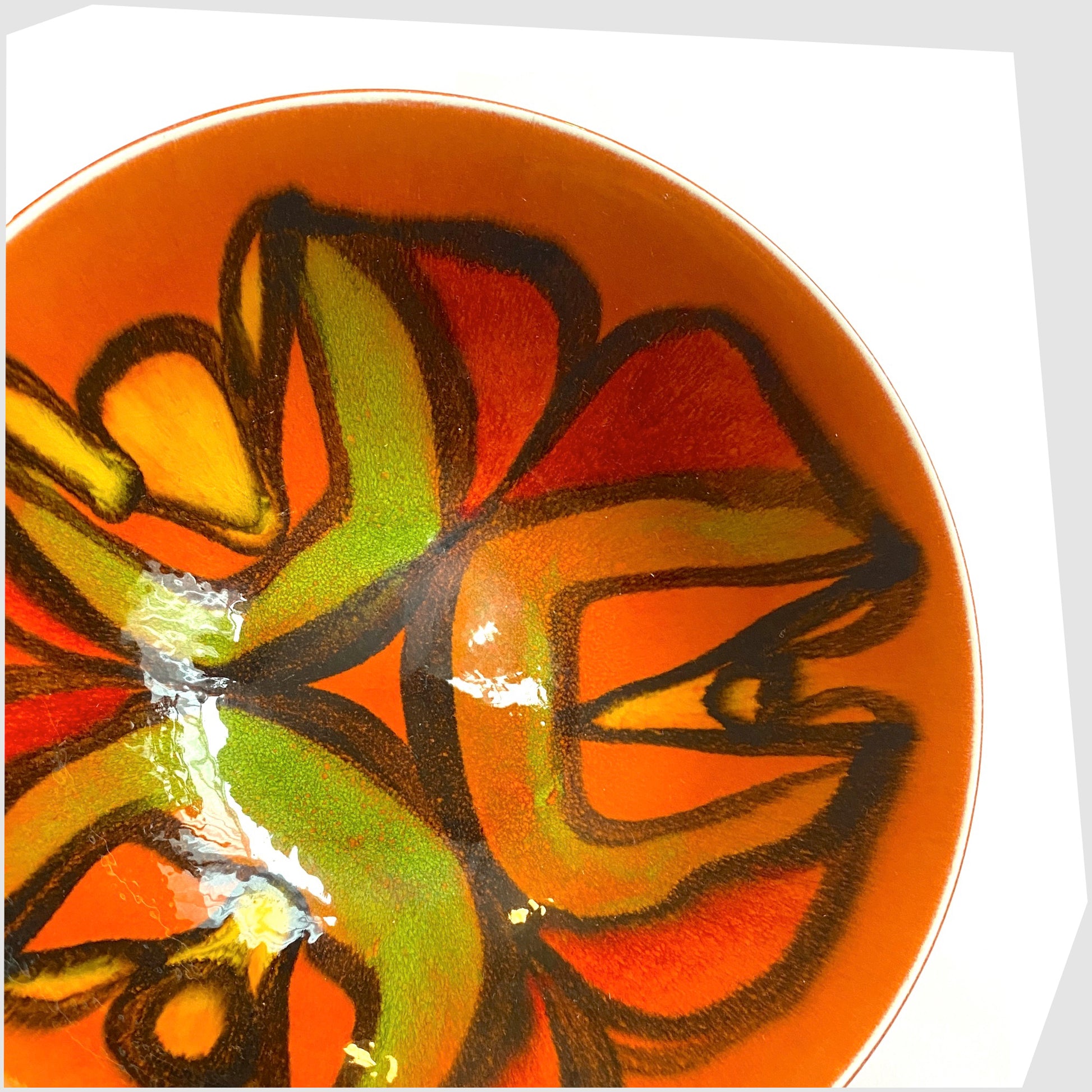 close up of the Poole Pottery Delphis Bowl, shape 56, by Cynthia Bennett, glazed in a vivid orange with arching forms of green, red, yellow and green.