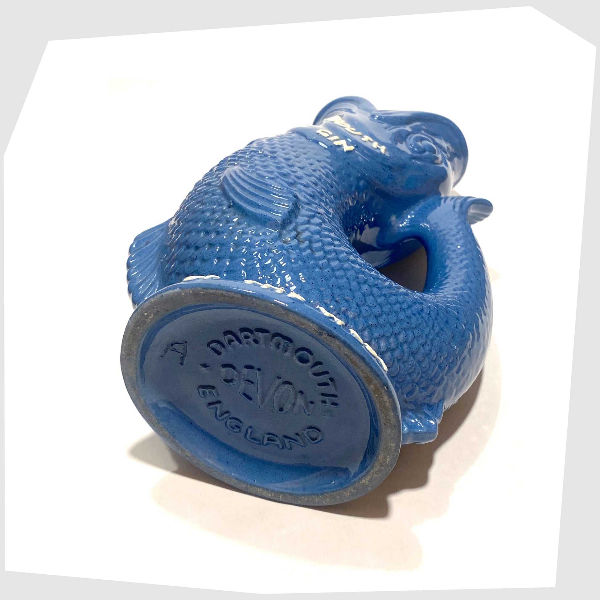 Base of the Dartmouth Pottery Plymouth Gin Gluggle in a sea blue glaze with white text around the spout and base