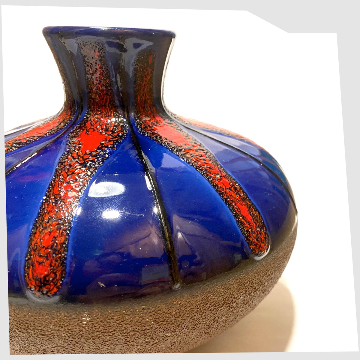 Close up of the Dumler and Breiden Vase with a contrasting glaze of matte natural glaze and vivid blue and red fat lava, shown on a white background