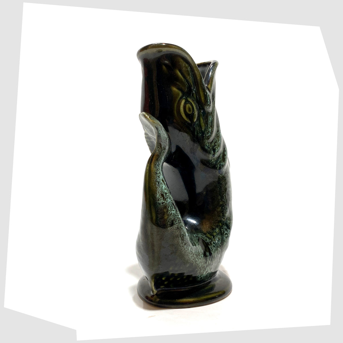 Handle of the fish-shaped Fosters Studio Pottery Gluggle Jug in green drip glaze, shown on a white background
