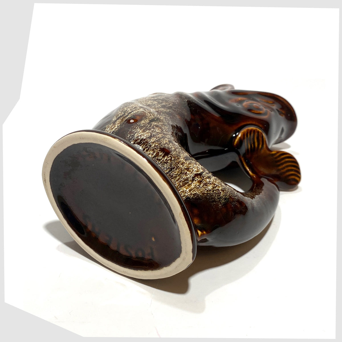 Base of the Fosters Studio Pottery Gluggle Jug in a chestnut brown with amber drip glaze, shown on a white background