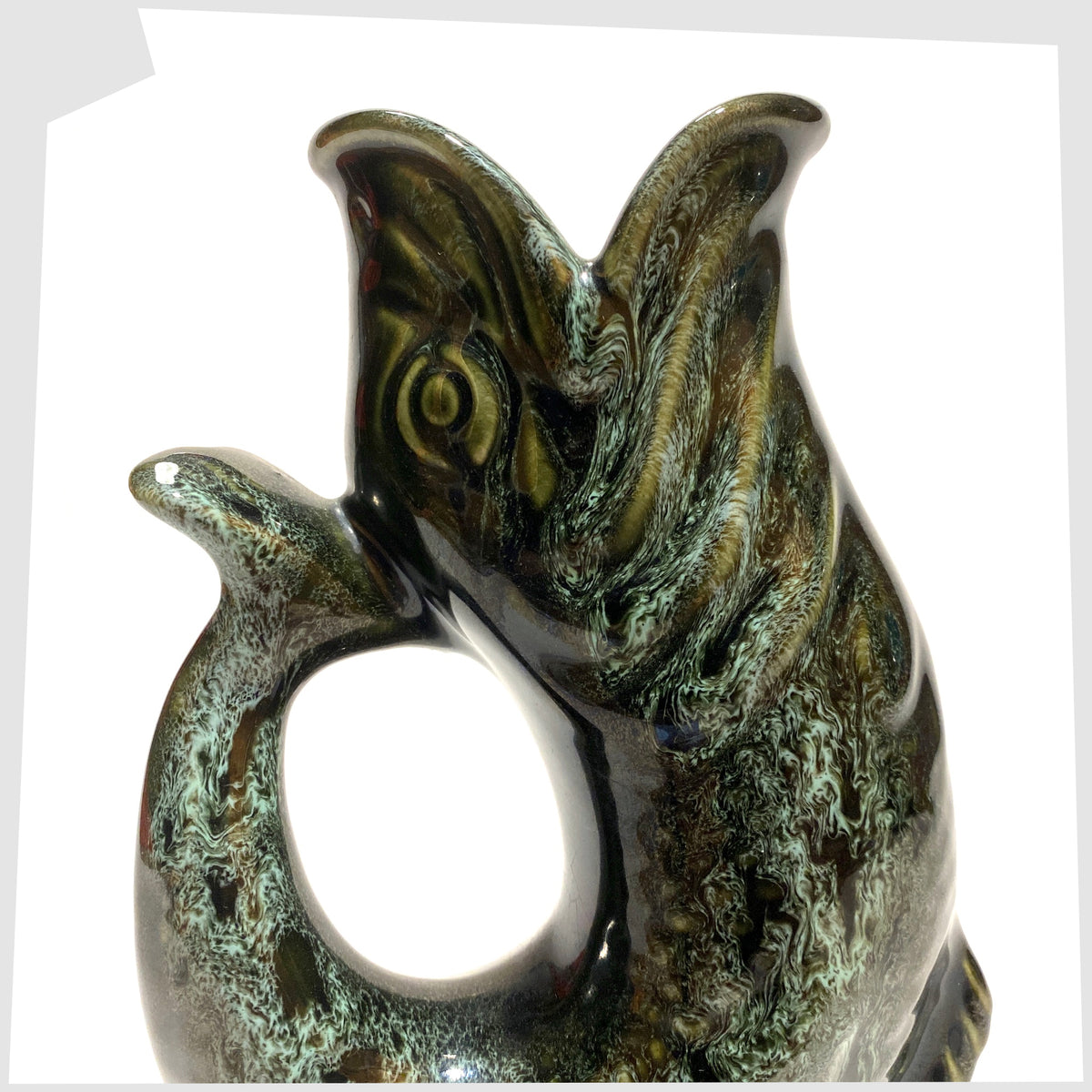 Close up of the Fosters Studio Pottery Gluggle Jug in green drip glaze, shown on a white background