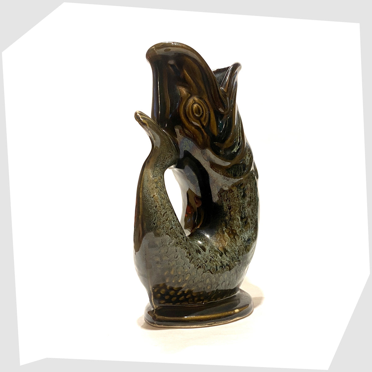 Handle of the vintage Fosters Studio Pottery Gluggle in Green honeycomb drip glaze, shown on a white background