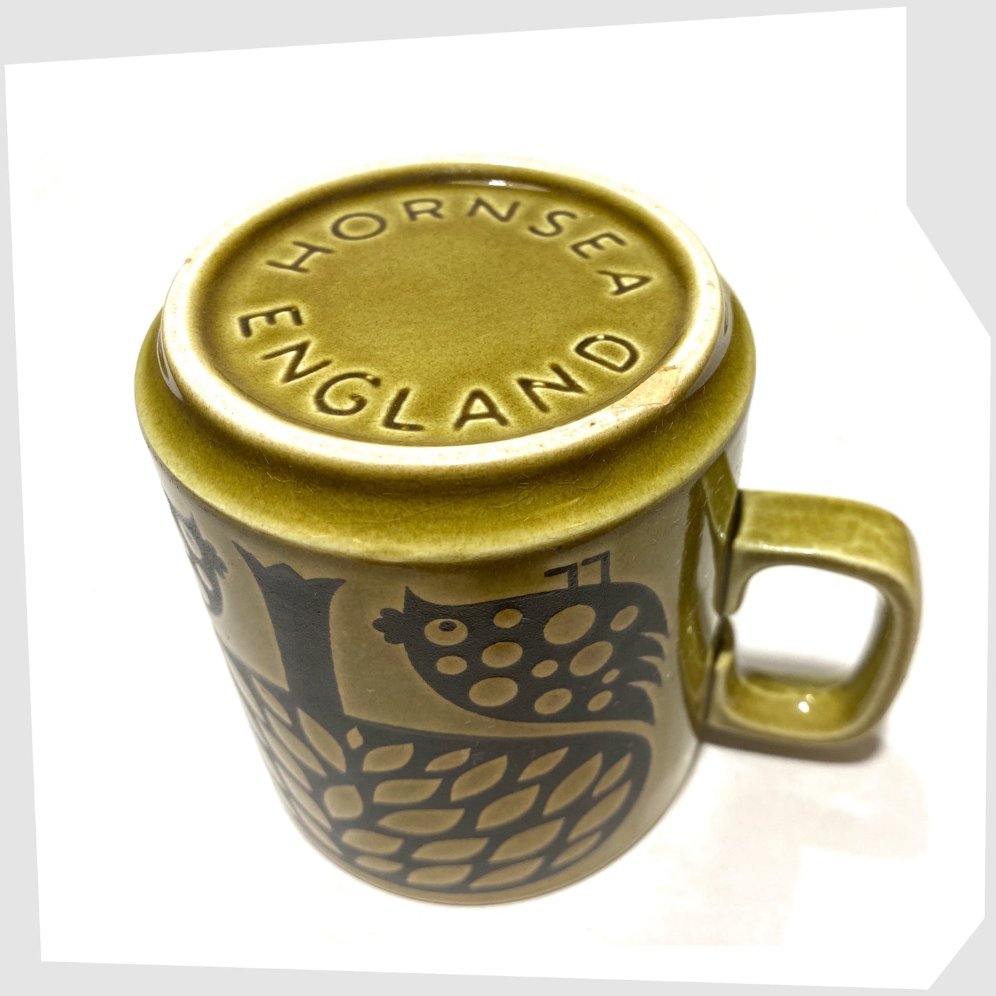 Underneath of the Original Hornsea Pottery Mug featuring a pair of partridge birds at the base of a tree, in an olive green glaze with lack decals, shown on a white background