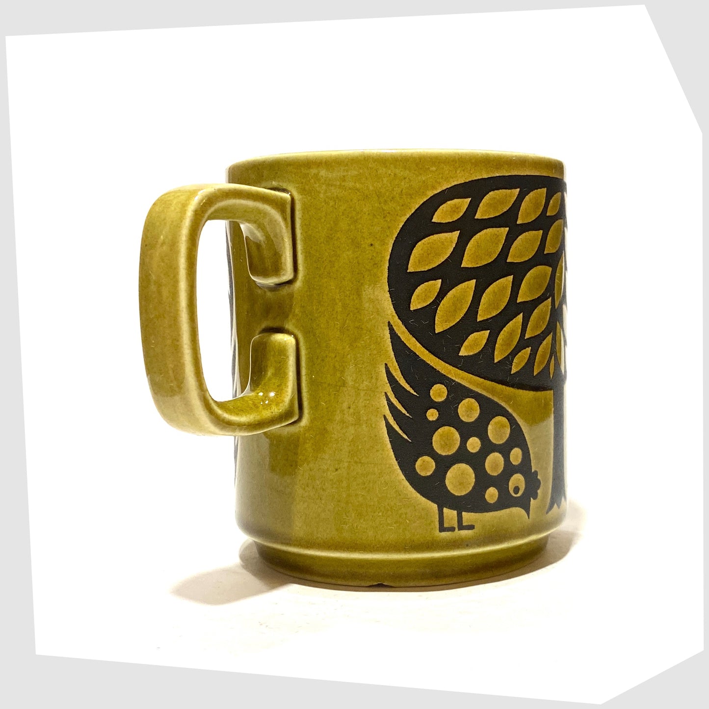 Handle of the Original Hornsea Pottery Mug featuring a pair of partridge birds at the base of a tree, in an olive green glaze with lack decals, shown on a white background