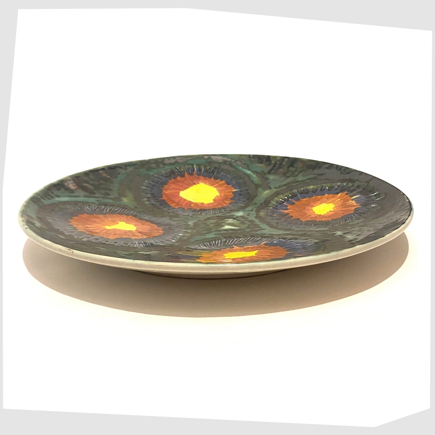 vintage charger plate by iden pottery in rye, with sea green and black glaze and circles of yellow, red and blue