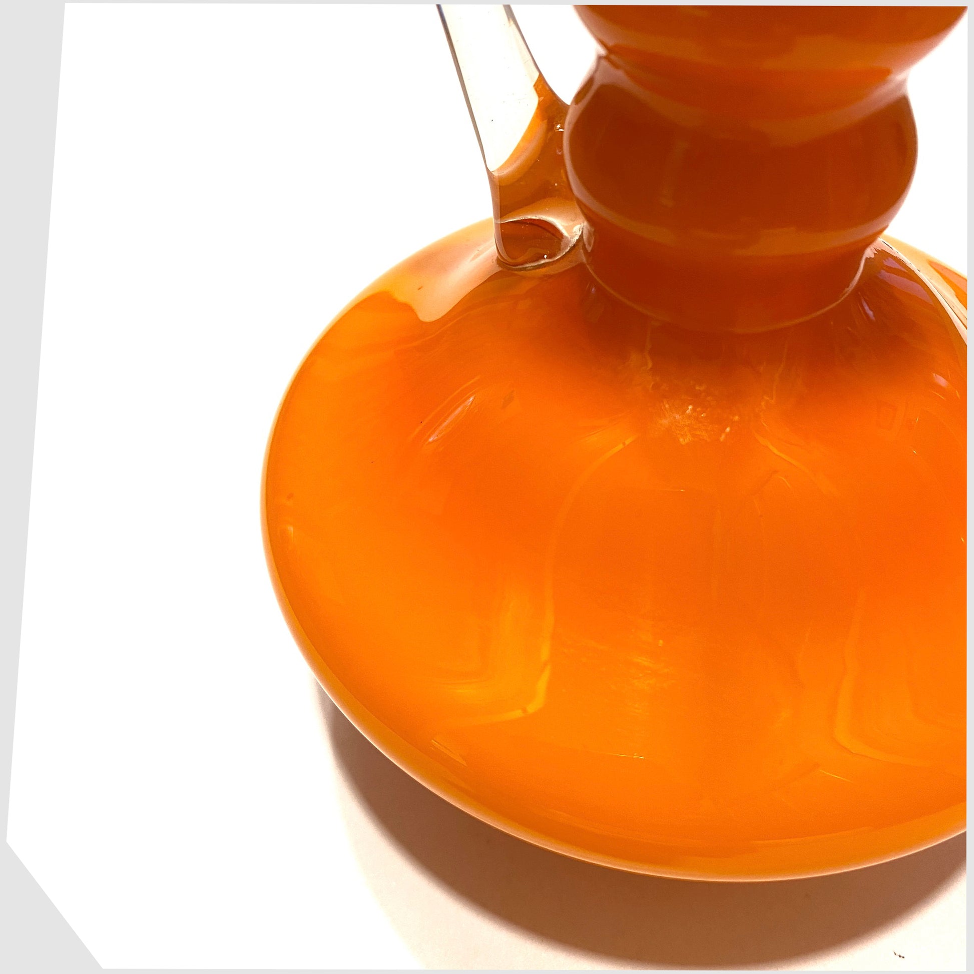 main curved body of the italian empoli glass jug in vibrant orange cased glass with clear glass handle