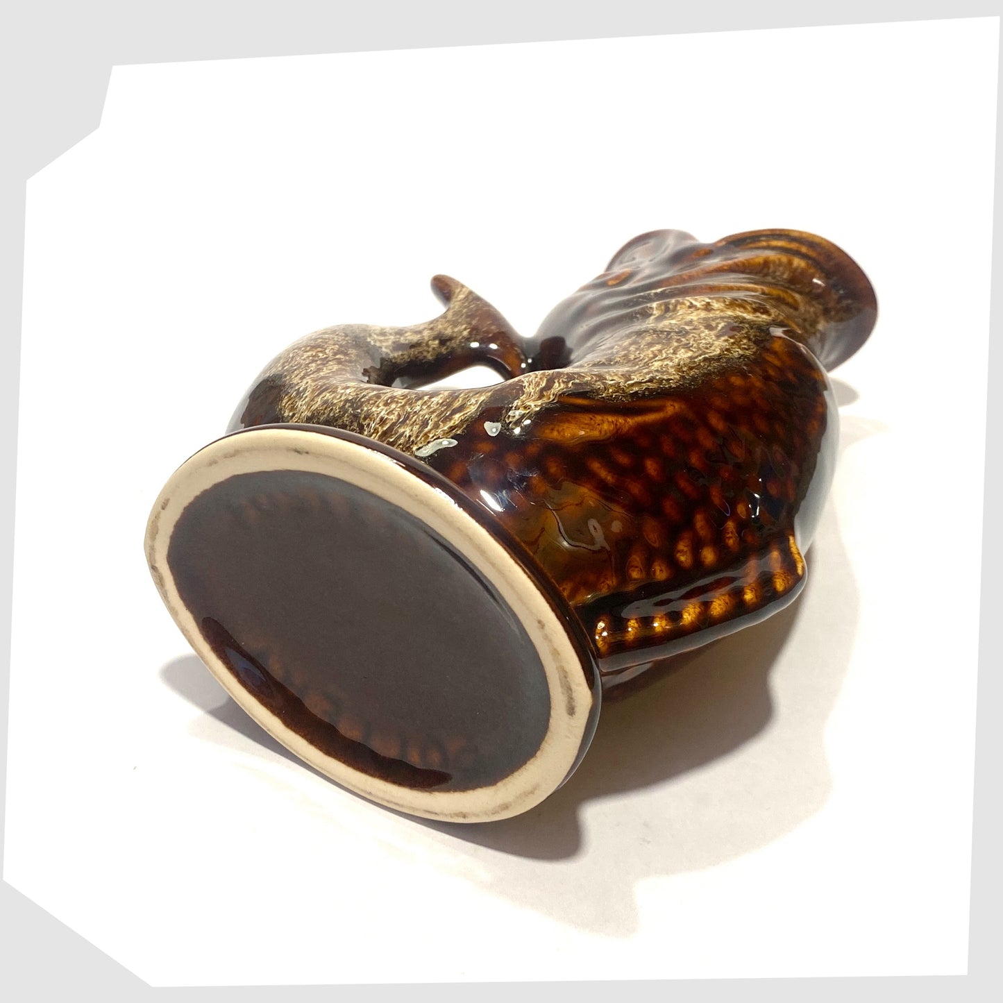 Base of the Fosters Studio Pottery Glugglr Jug in a chestnut brown with amber drip glaze, shown on a white background