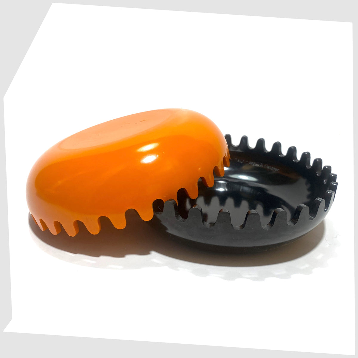 Open Clam Ashtray designed by Alan Fletcher for Pentagram Design in half orange and half black, shown on a white background