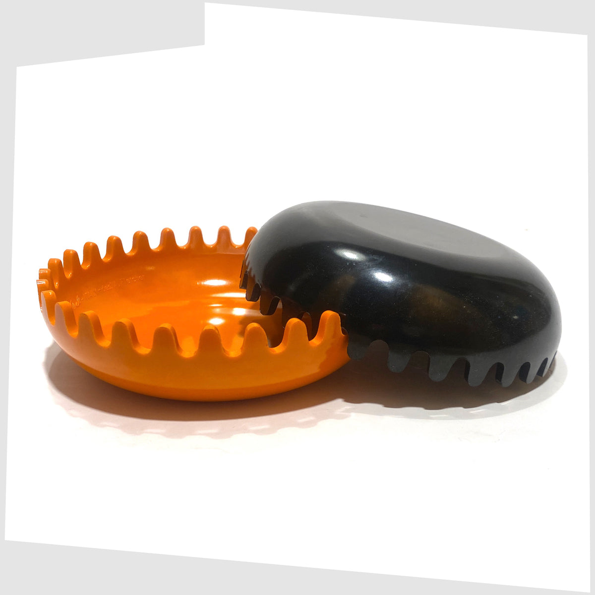 1972 Clam Ashtray designed by Alan Fletcher for Pentagram Design in half orange and half black, shown open on a white background
