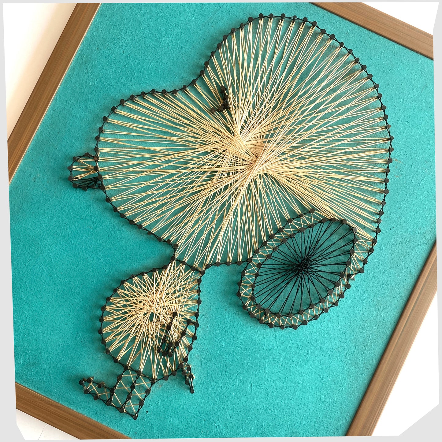 Close up of the Vintage Snoopy String Artwork, created from beige string and black nails on a teal background, shown on a white background