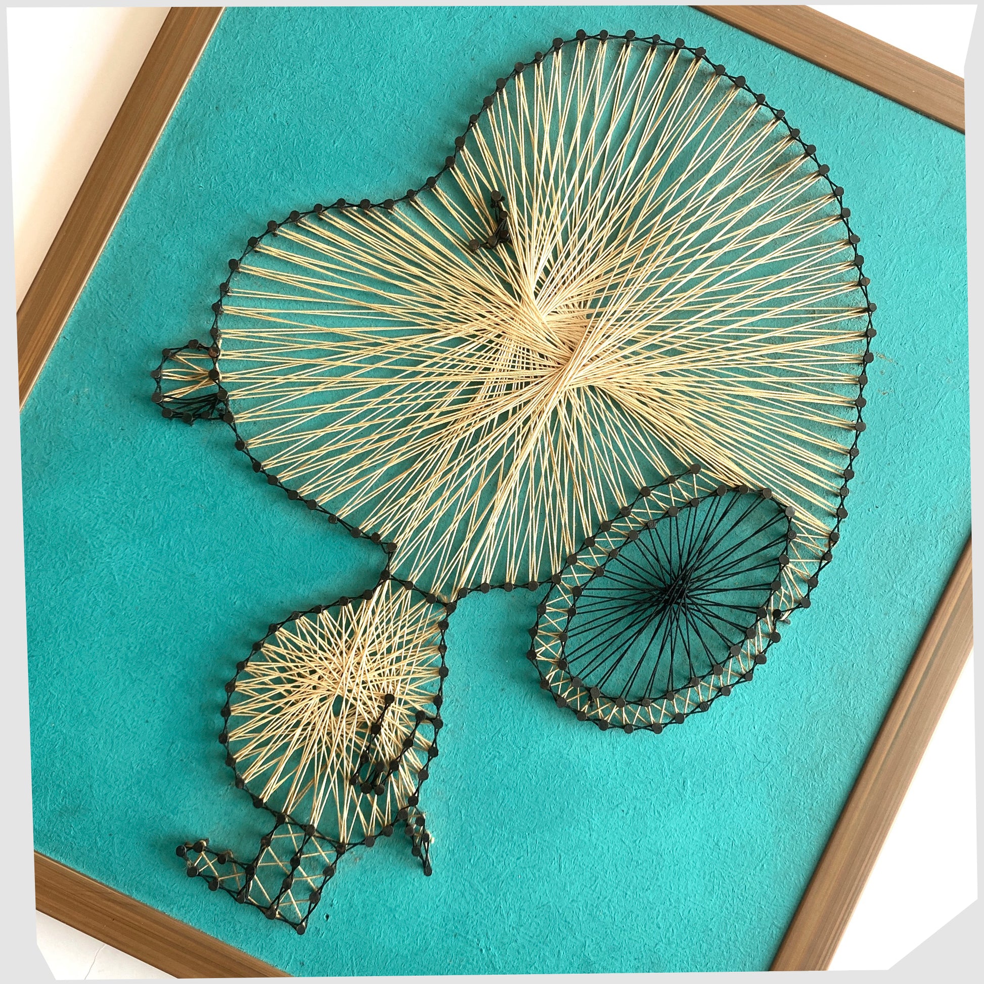 Close up of the Vintage Snoopy String Artwork, created from beige string and black nails on a teal background, shown on a white background