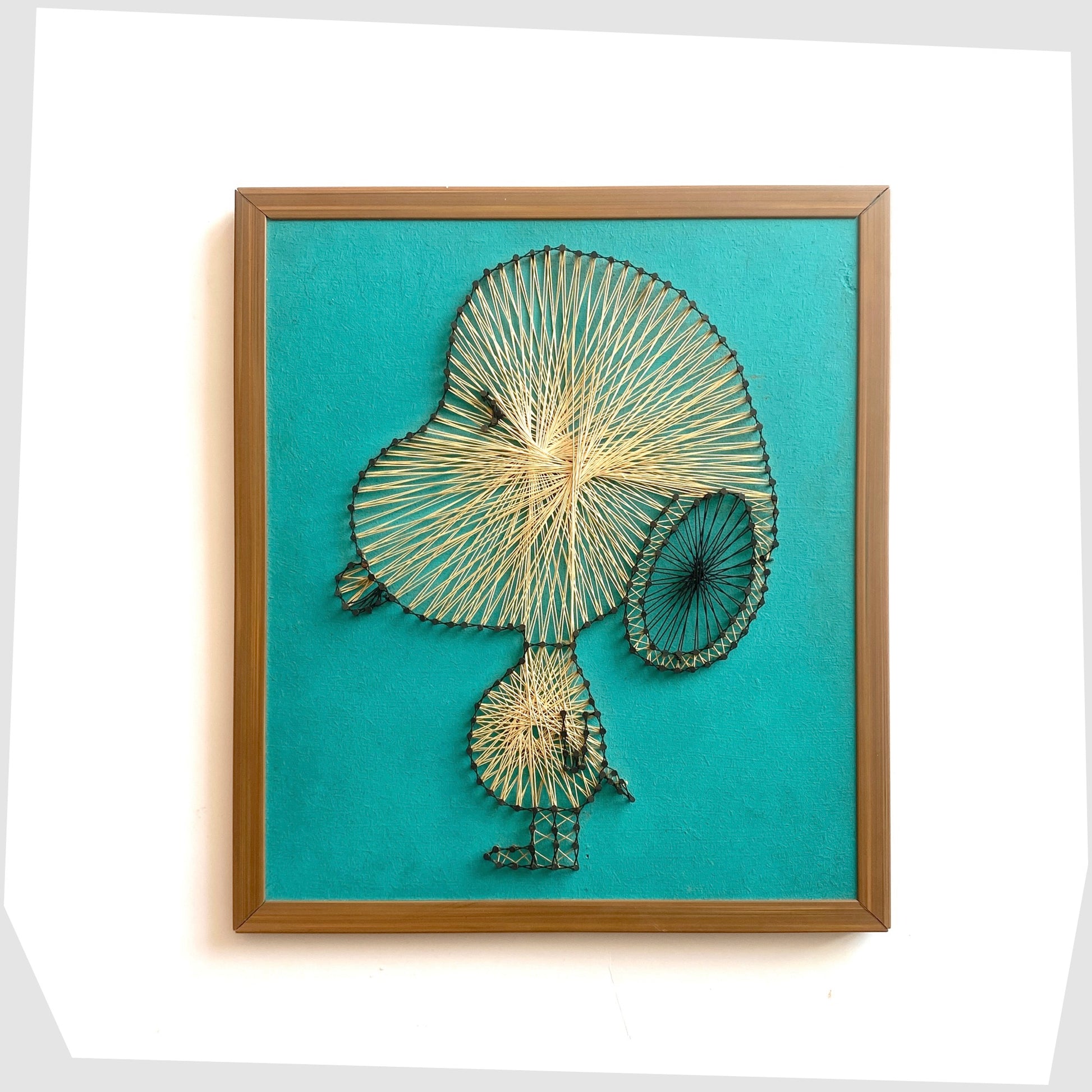 Vintage Snoopy String Artwork, created from beige string and black nails on a teal background, shown on a white background