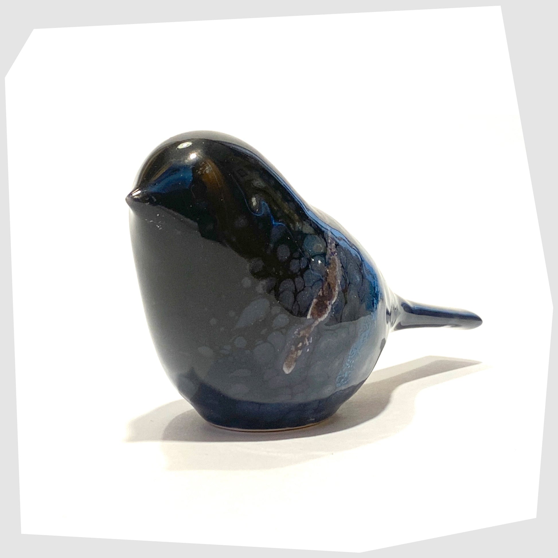 front of the poole pottery ceramic bird ornament in celestial glaze of black with blue and purple tones
