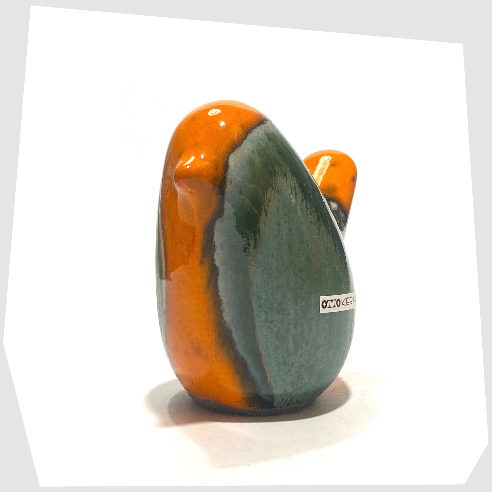 Front of the Otto Keramik Ceramic Bird in Peru glaze of orange with sea green drip glaze, shown on a white background