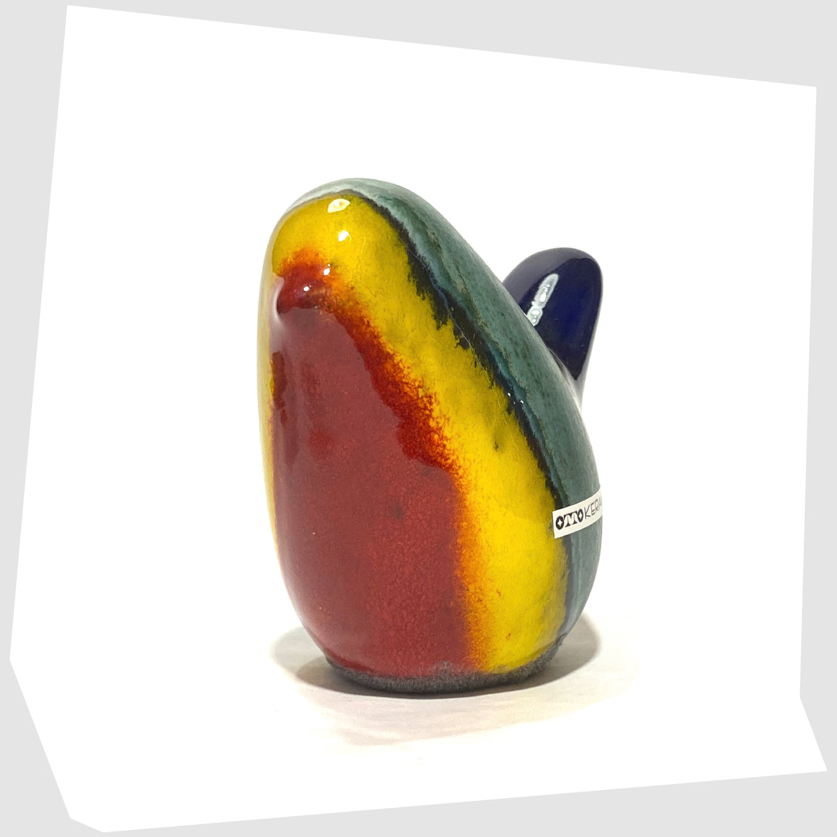 ceramic bird by otto keramik in multicoloured rainbow glaze of red, yellow, green and dark blue, shown on a hite background