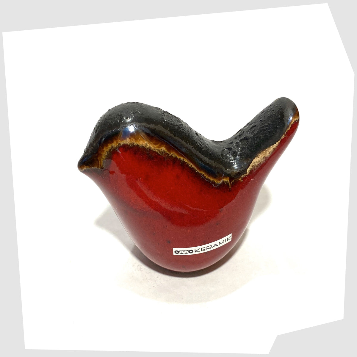 top view of the Otto Keramik ceramic bird in red glaze with grey fat lava along the spine, shown on a white background