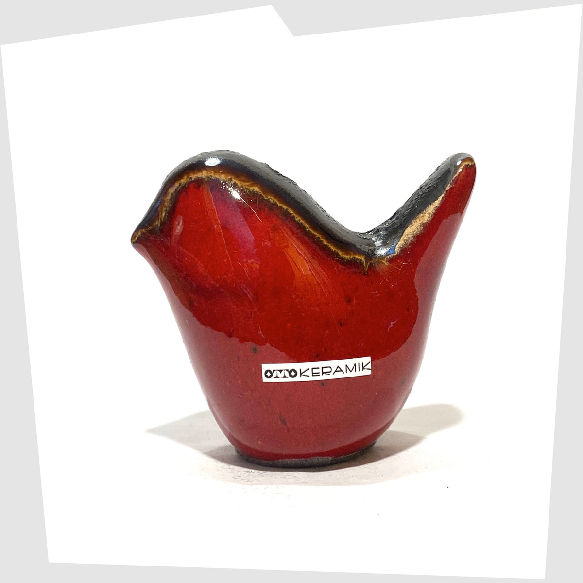 Otto Keramik ceramic bird in red glaze with grey fat lava along the spine, shown on a white background