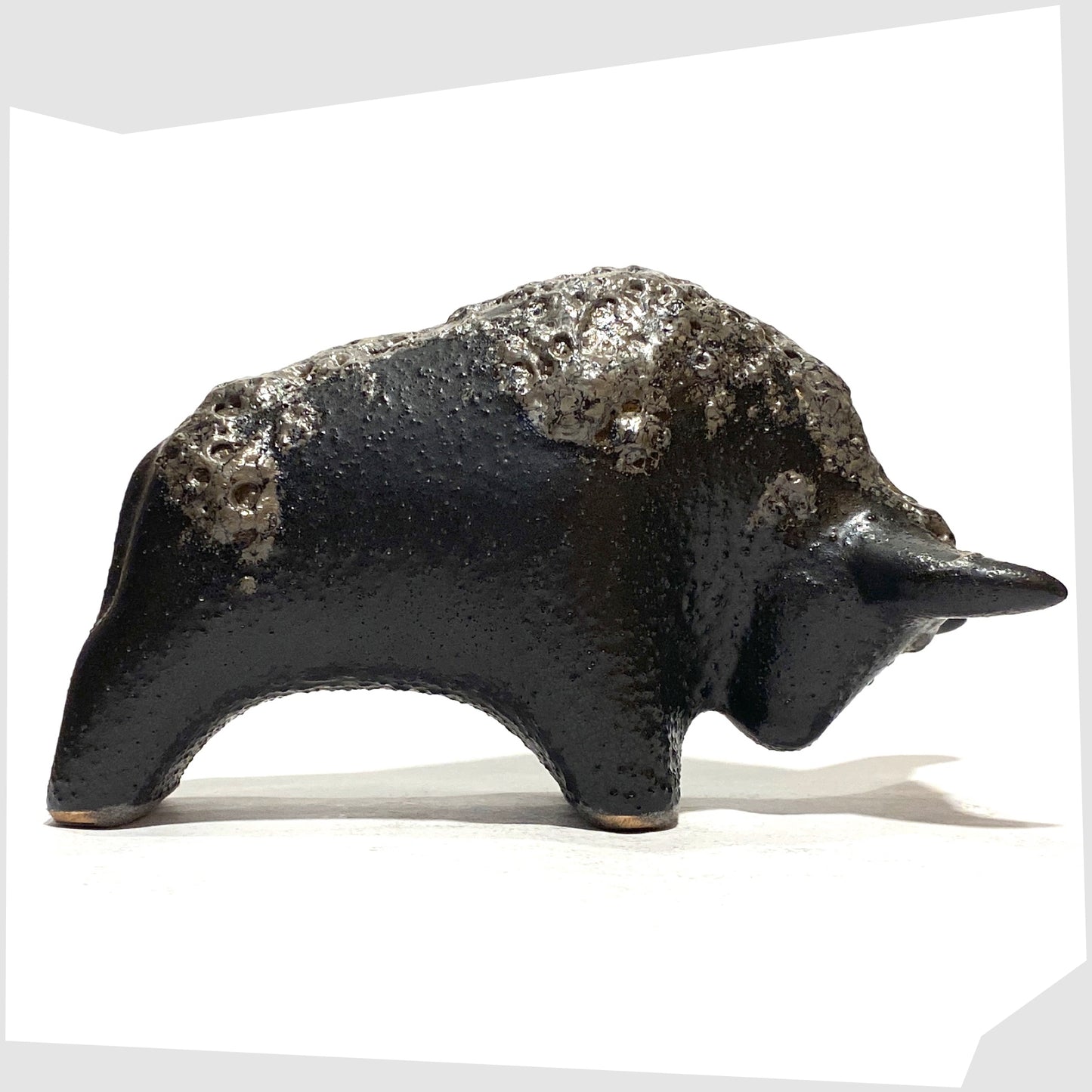 Otto Keramik Bull in textured black glaze with deep fat lava glazing along the spine, shown on a white background