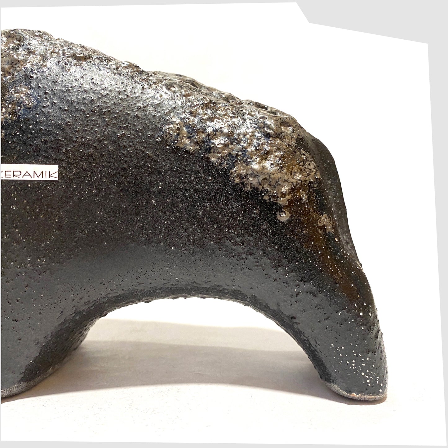 Glazing detail on the Otto Keramik Bull with textured black glaze with deep fat lava glazing along the spine, shown on a white background