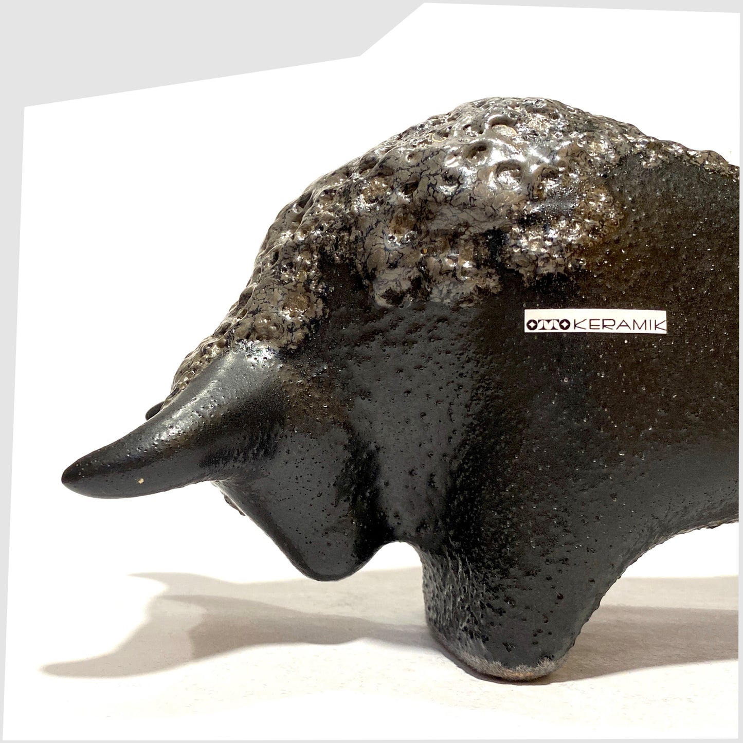 Close up of the Otto Keramik Bull in textured black glaze with deep fat lava glazing along the spine, shown on a white background