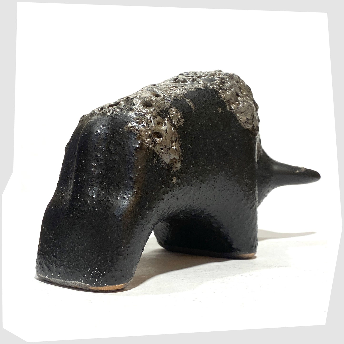 Rear of the Otto Keramik Bull in textured black glaze with deep fat lava glazing along the spine, shown on a white background