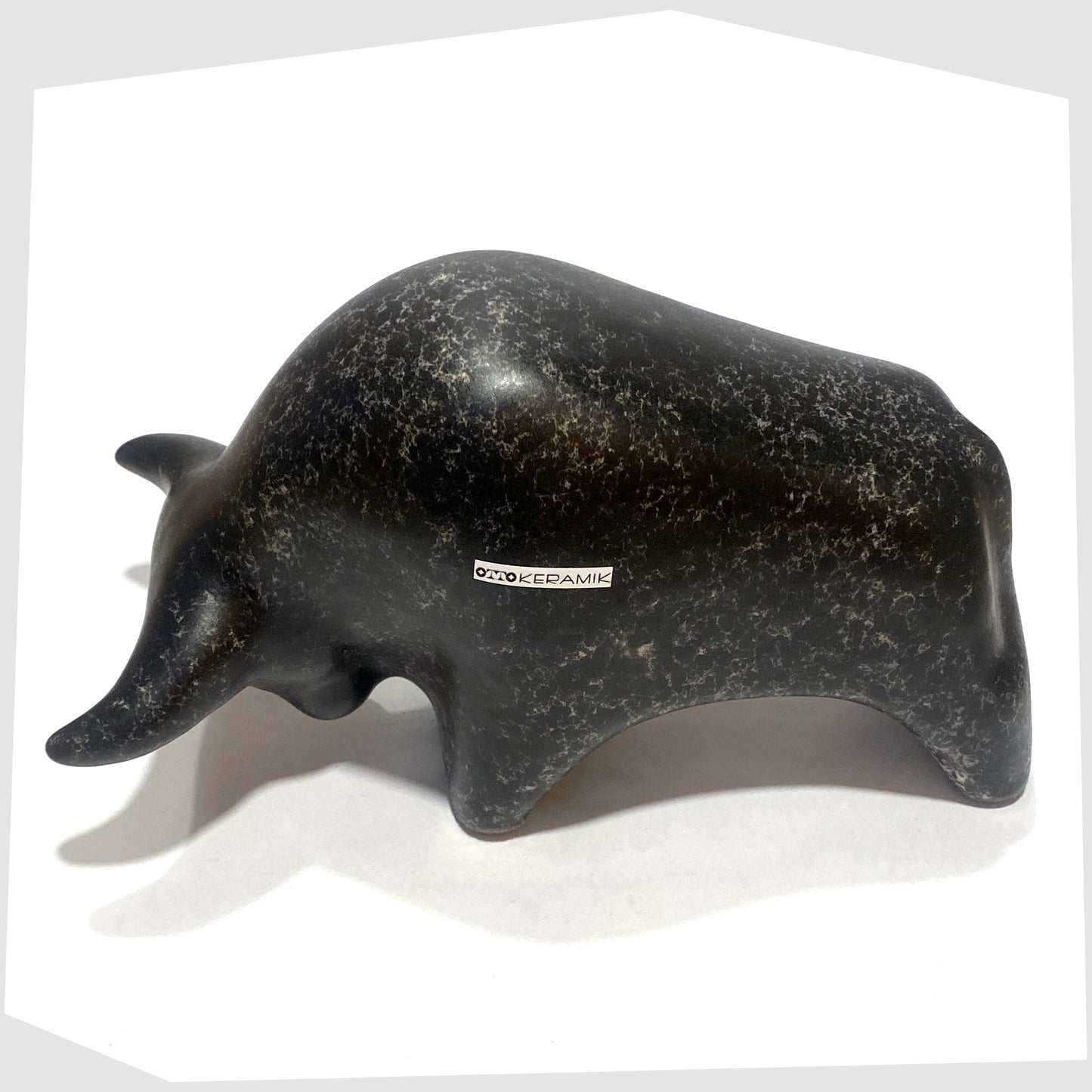 Overhead angle of the Otto Keramik ceramic bull-shaped figurine in black speckled glaze, shown on a white background