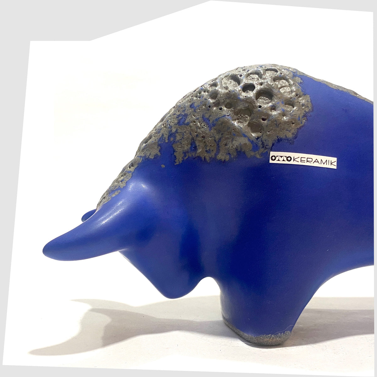 Close up of the Otto Keramik Bull-shaped ceramic ornament in blue with grey fat lava glaze, shown on a white background